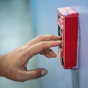 Close up of hand testing manual pull station of building fire safety system