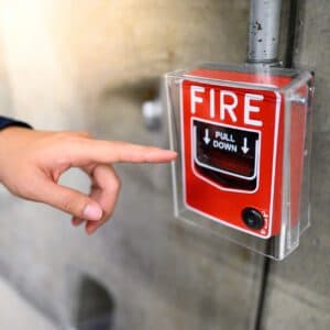 NICET technician demonstrating compliance test of emergency fire alarm pull station
