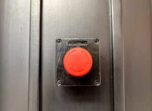 Red alarm trigger device mounted to dark wall