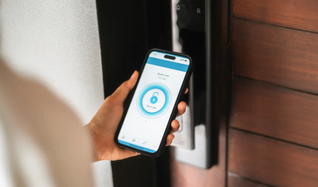 A hand holding a smartphone showing a smart home lock control app in front of a wooden door