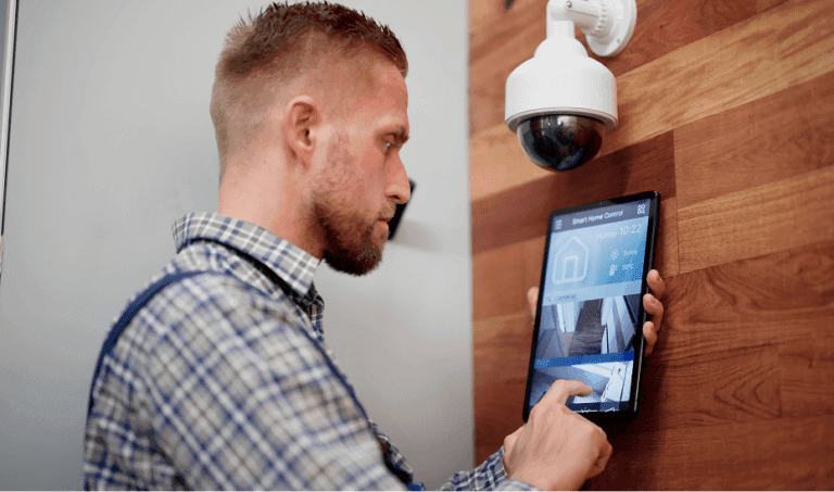 A professional security technician checking a security camera on a wood-paneled wall