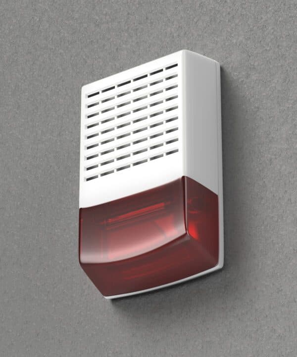 An indoor/outdoor wall siren with red strobe warning light mounted on a grey textured stucco wall