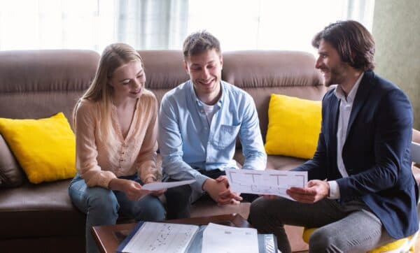 Leasing agent showing apartment floor plan to a couple on a sofa