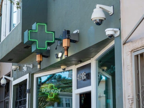Exterior view of a pharmacy dispensary storefront with outdoor security cameras installed