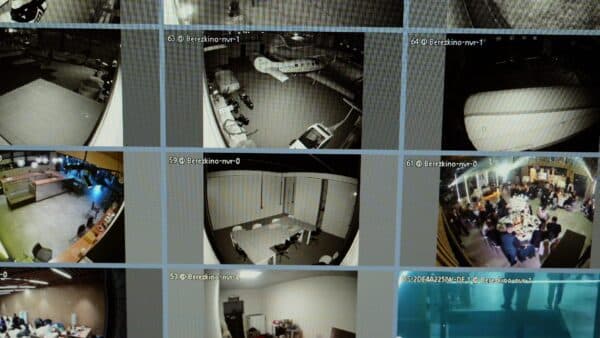Multiple security camera feeds displayed on a monitoring screen showing kitchen, office, and dining areas