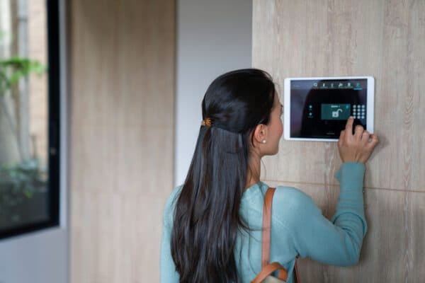 Woman using a smart security keypad mounted on a wall
